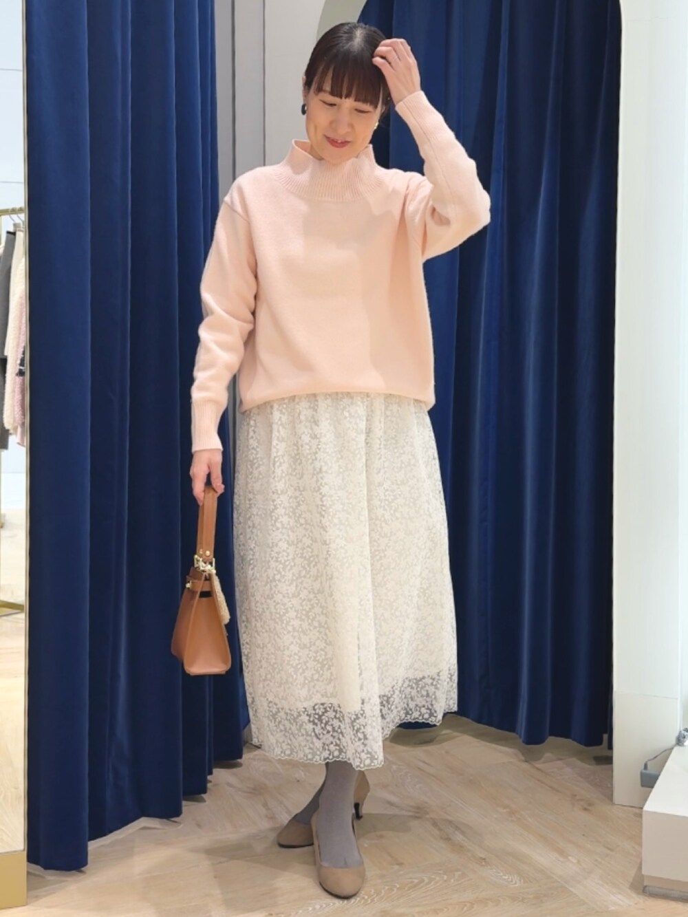 ピンク系のニット/セーター、イエロー系のショルダーバッグ、ホワイト系のスカートを着用したレディースの冬コーディネートの5枚目の写真