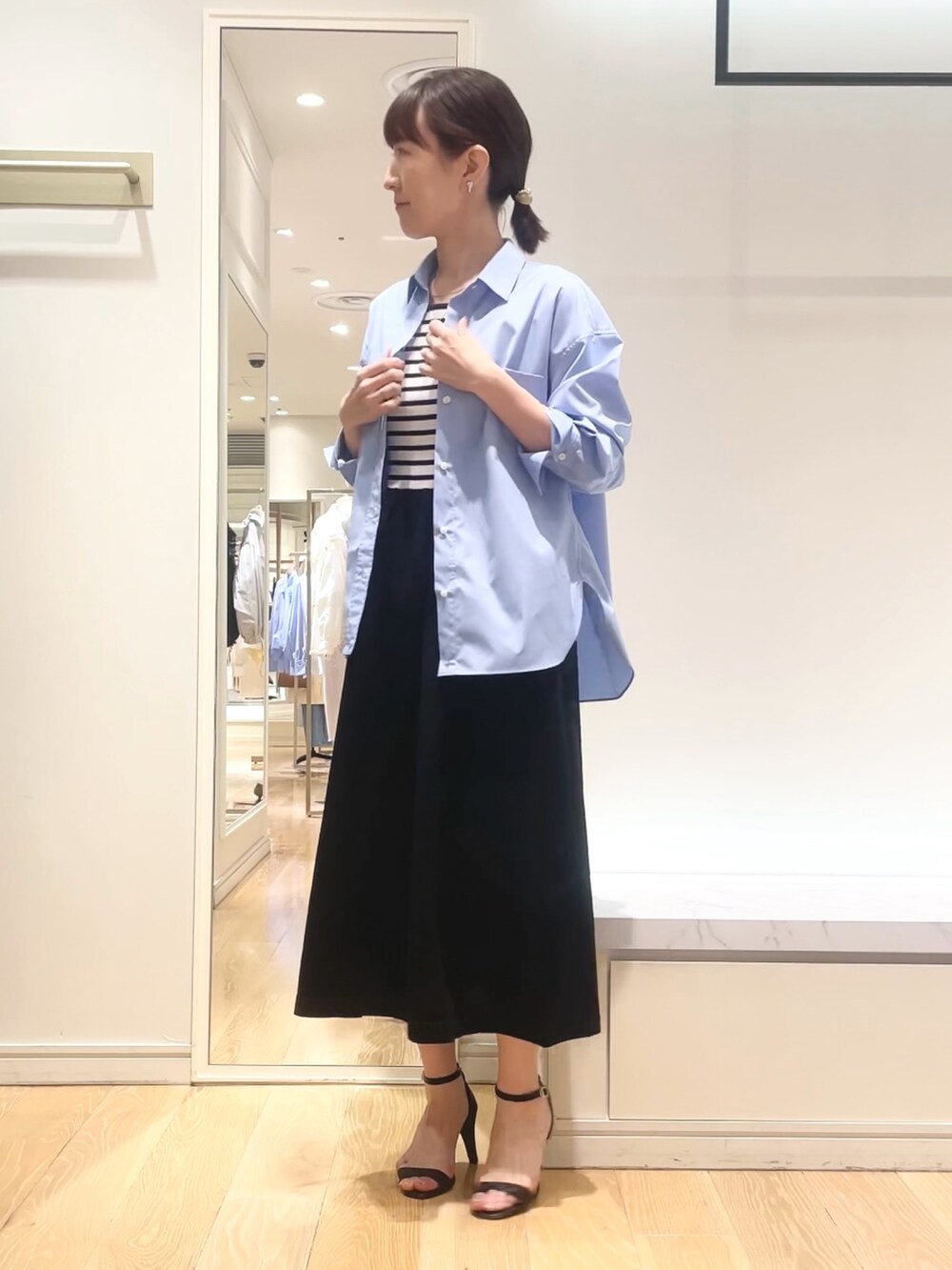 ブルー系のシャツ/ブラウス、ブラック系のワンピース、ゴールド系のイヤリングを着用したレディースの春コーディネートの6枚目の写真