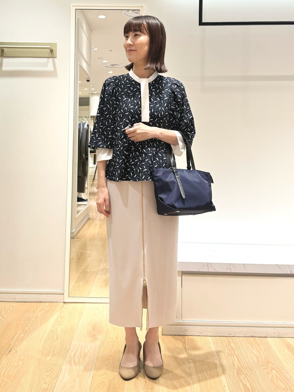 ベージュ系のスカート、ブルー系のトートバッグ、ブルー系のシャツ/ブラウスを着用したレディースの秋コーディネートの2枚目の写真