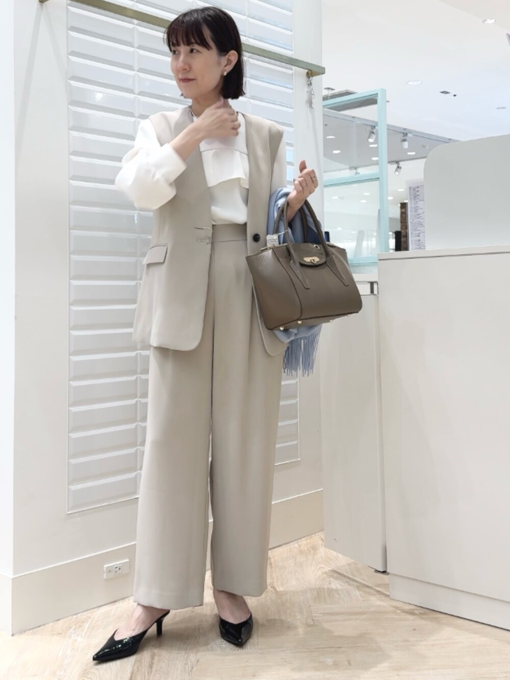 ブラウン系のショルダーバッグ、ベージュ系のその他パンツ、ベージュ系のベストを着用したレディースの秋コーディネートの4枚目の写真