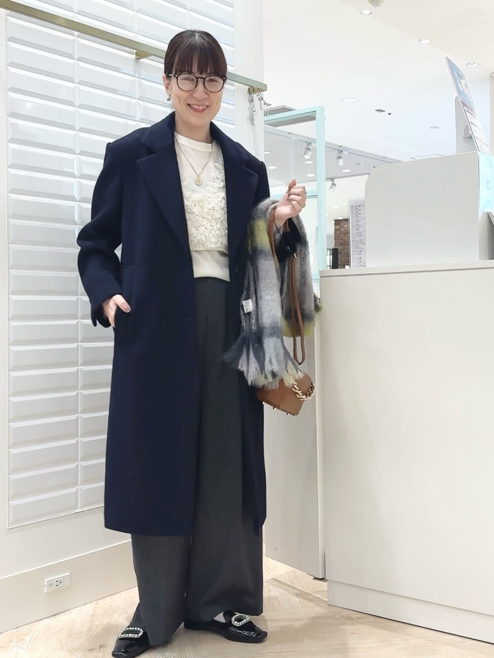 グレー系のその他パンツ、ブルー系のチェスターコート、ホワイト系のベストを着用したレディースの秋コーディネートの4枚目の写真