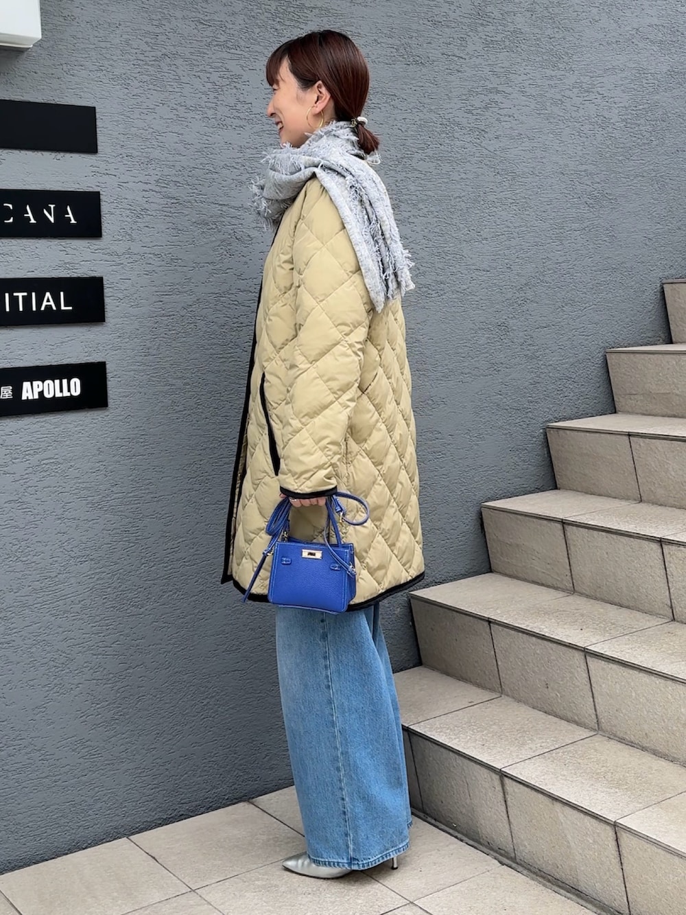 ブルー系のデニムパンツ、ブルー系のショルダーバッグ、ベージュ系のダウンジャケット/コートを着用したレディースの秋コーディネートの4枚目の写真