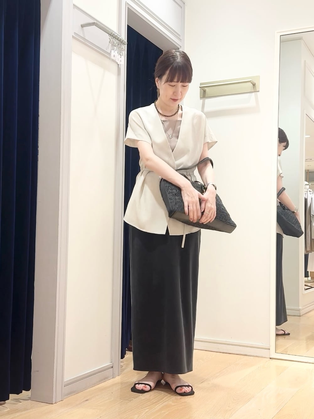 ブラック系のスカート、ブラック系のショルダーバッグ、ベージュ系のタンクトップを着用したレディースの夏コーディネートの5枚目の写真