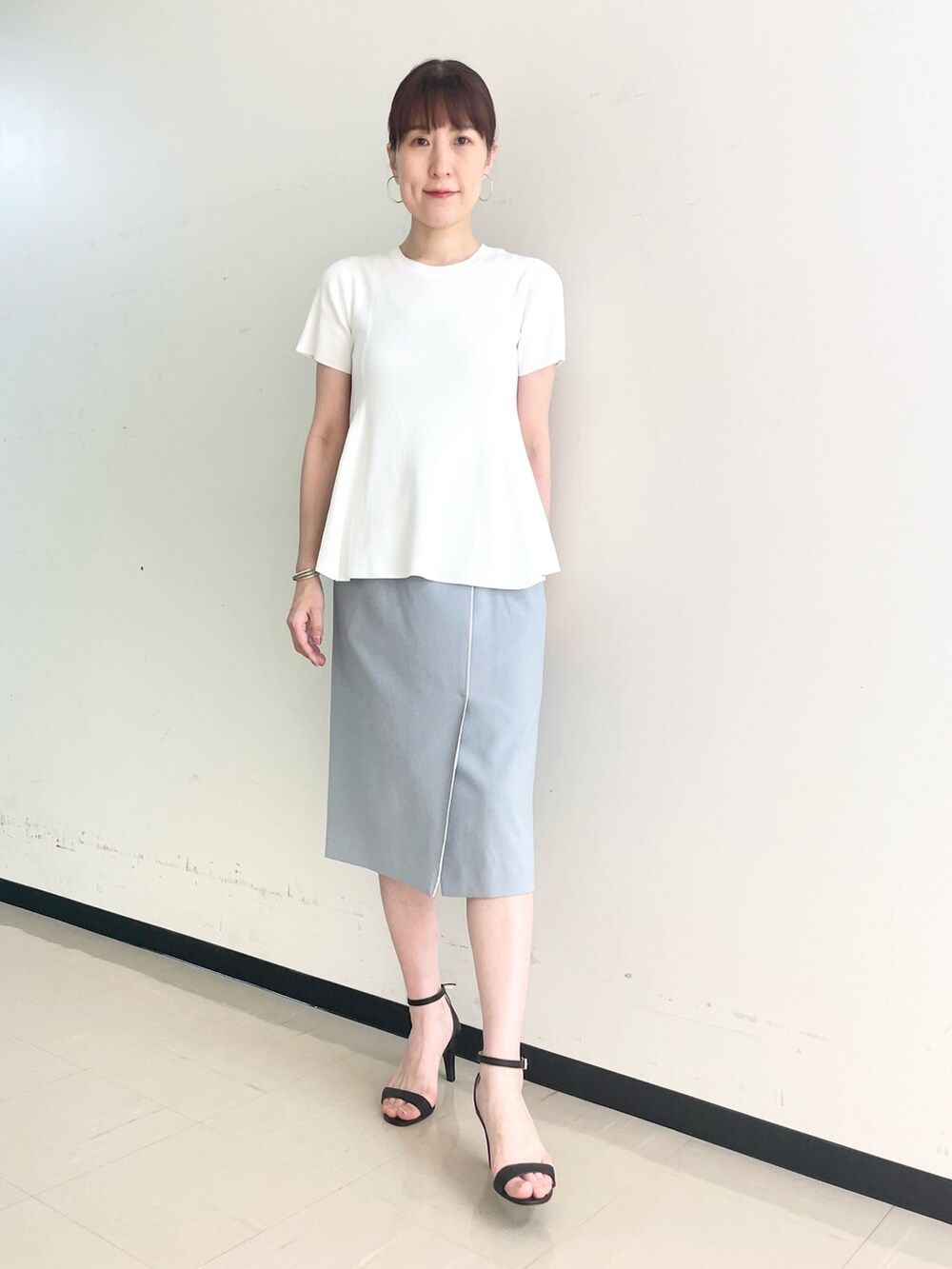 ブルー系のスカート、ホワイト系のニット/セーターを着用したレディースの春コーディネートの4枚目の写真