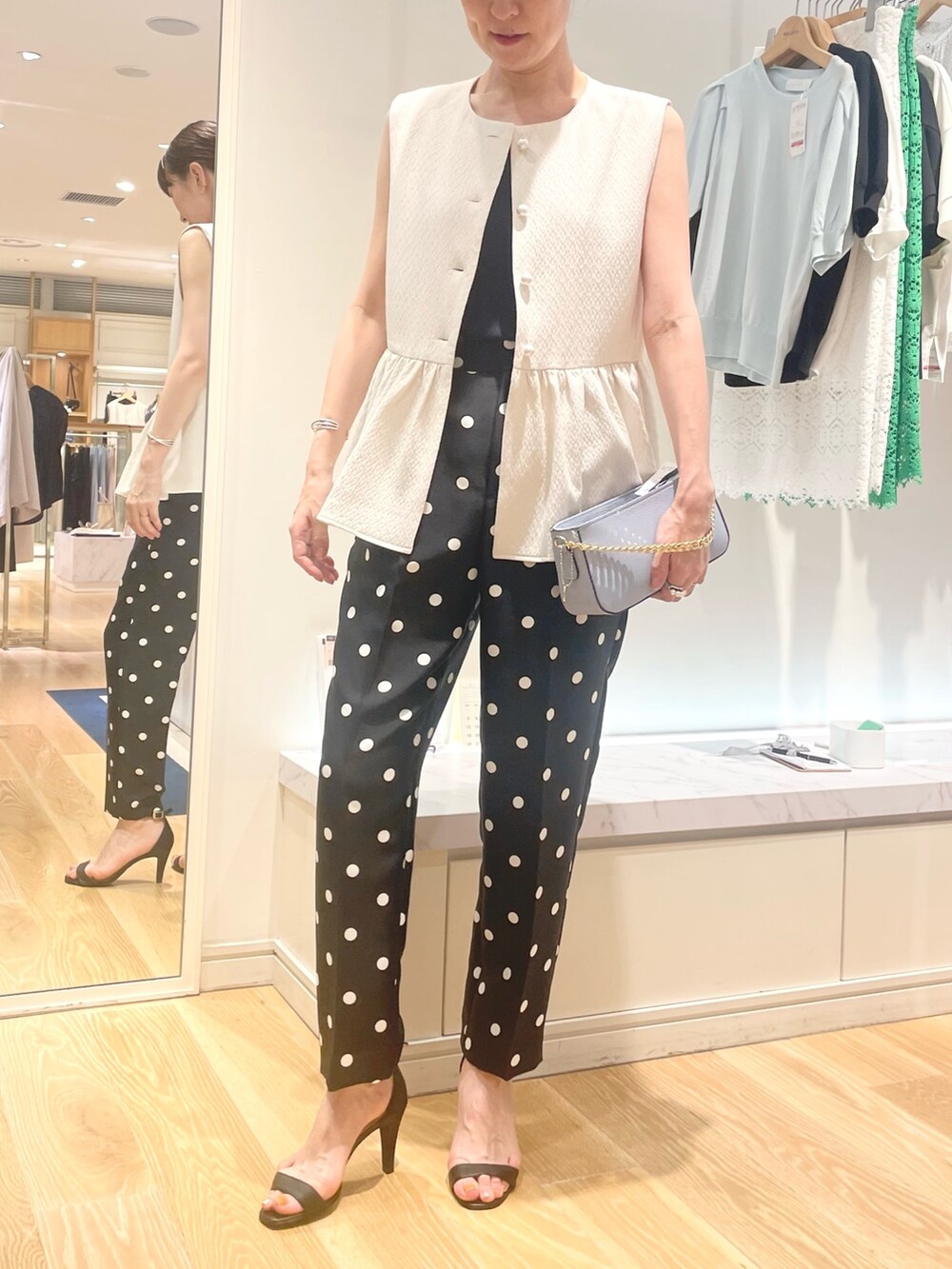 ホワイト系のベスト、ブラック系のその他パンツ、ブルー系のショルダーバッグを着用したレディースの夏コーディネートの6枚目の写真