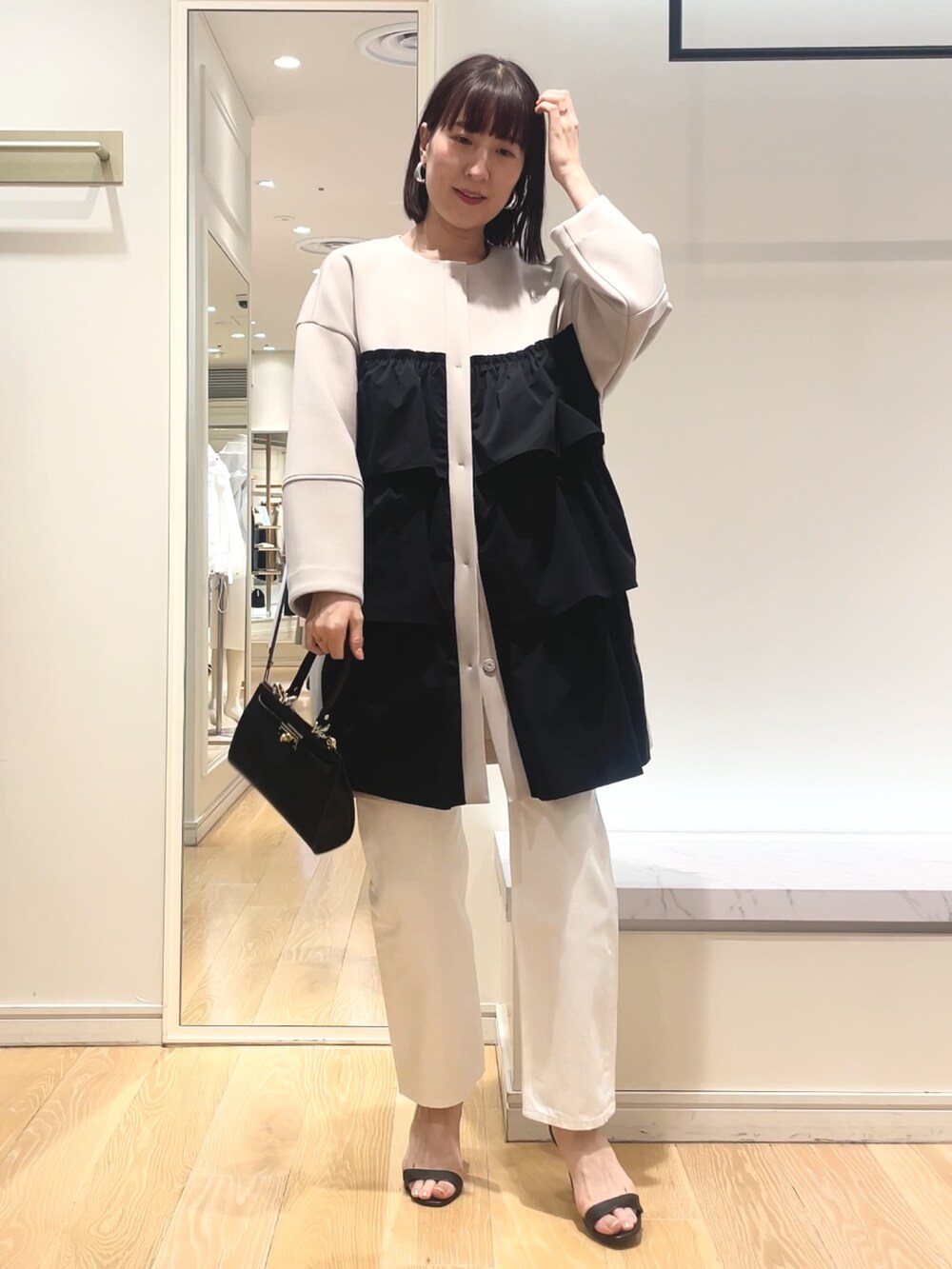 ベージュ系のその他アウター、ブラック系のショルダーバッグを着用したレディースの春コーディネートの2枚目の写真