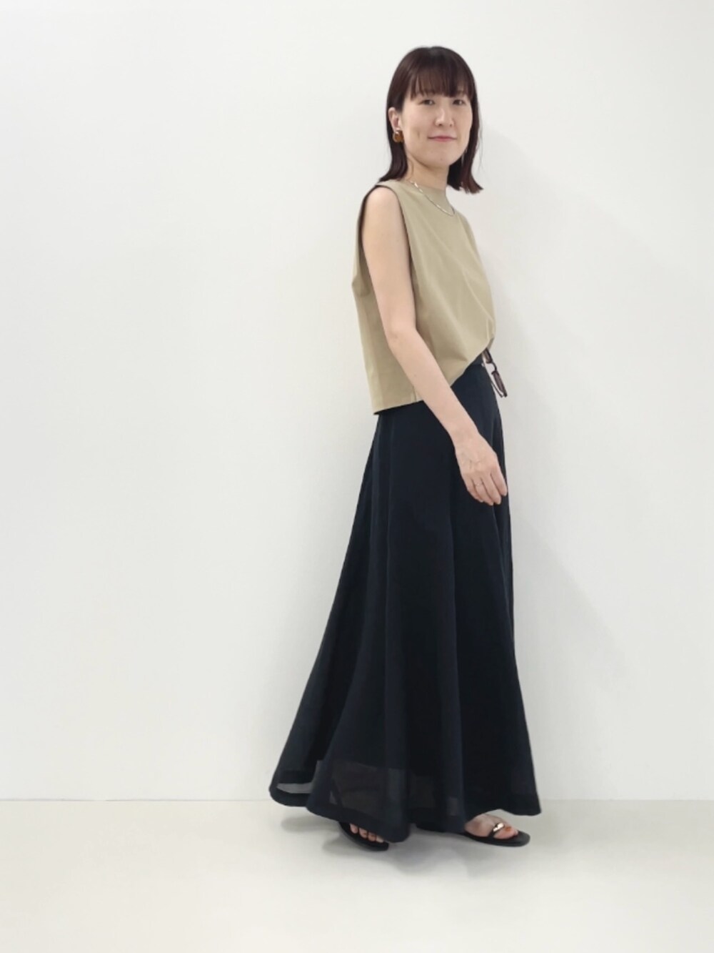 ブラック系のサンダル、ベージュ系のTシャツ/カットソー、ブラック系のスカートを着用したレディースの夏コーディネートの4枚目の写真