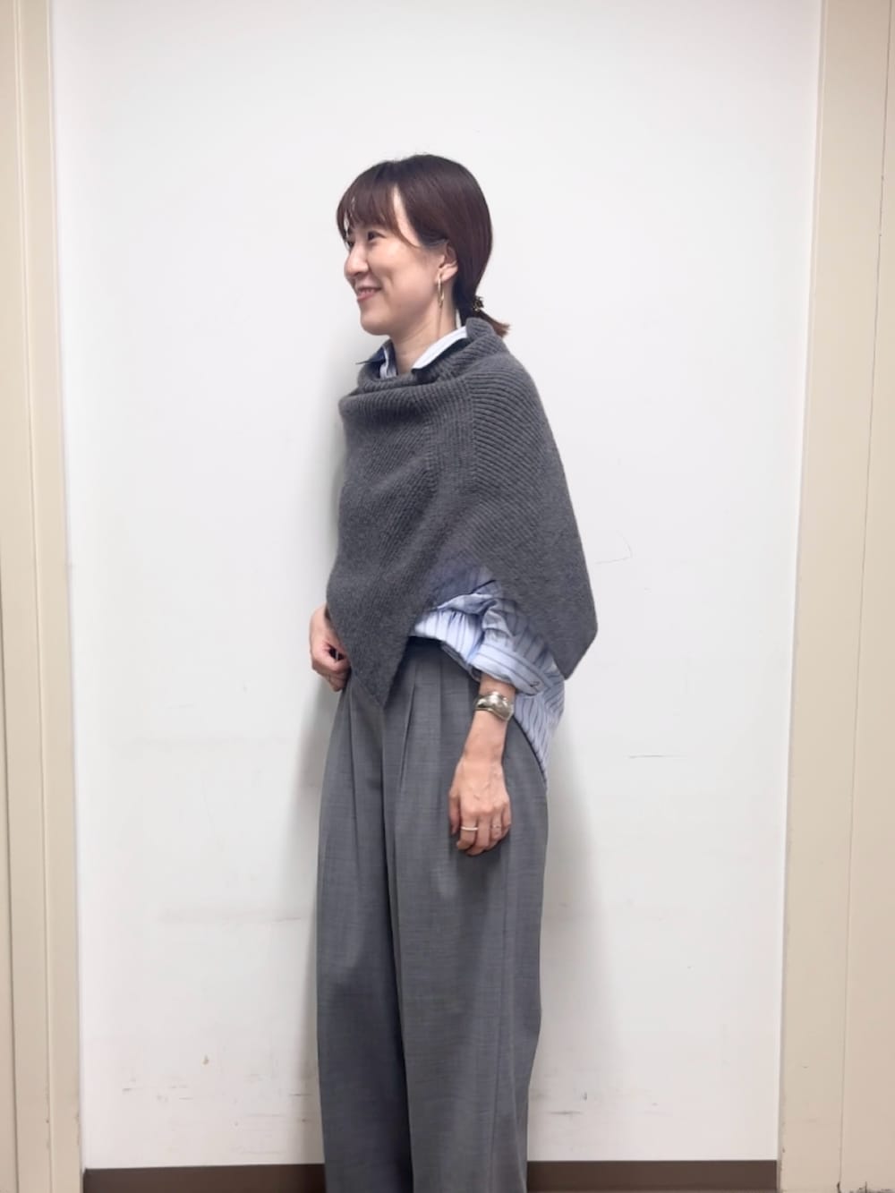 グレー系のニット/セーター、グレー系のその他パンツ、ブルー系のシャツ/ブラウスを着用したレディースの秋コーディネートの2枚目の写真