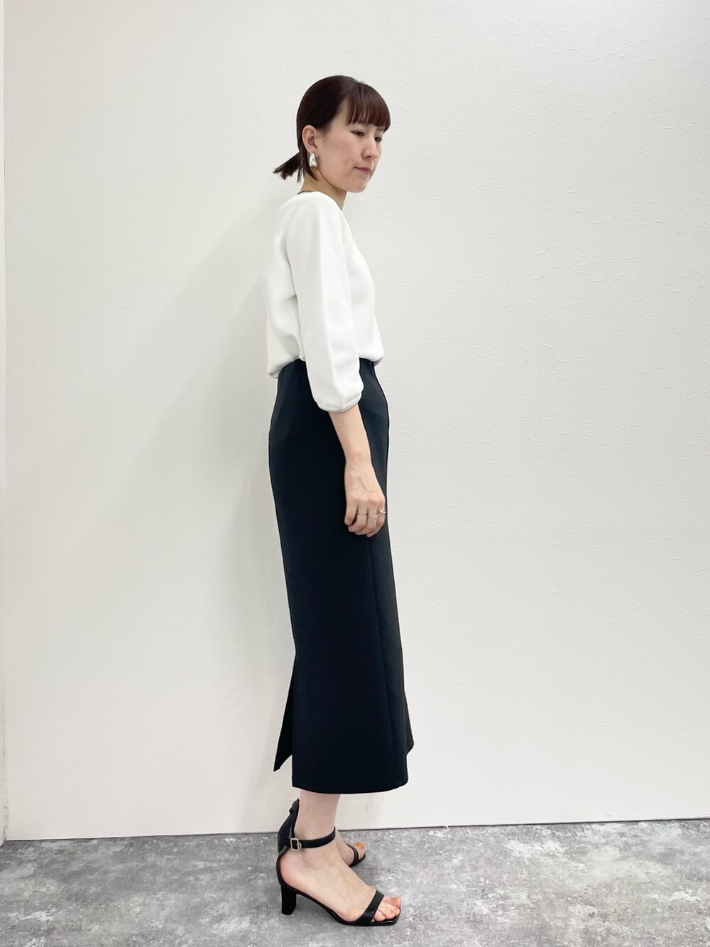 ブラック系のスカート、ホワイト系のニット/セーターを着用したレディースの春コーディネートの4枚目の写真