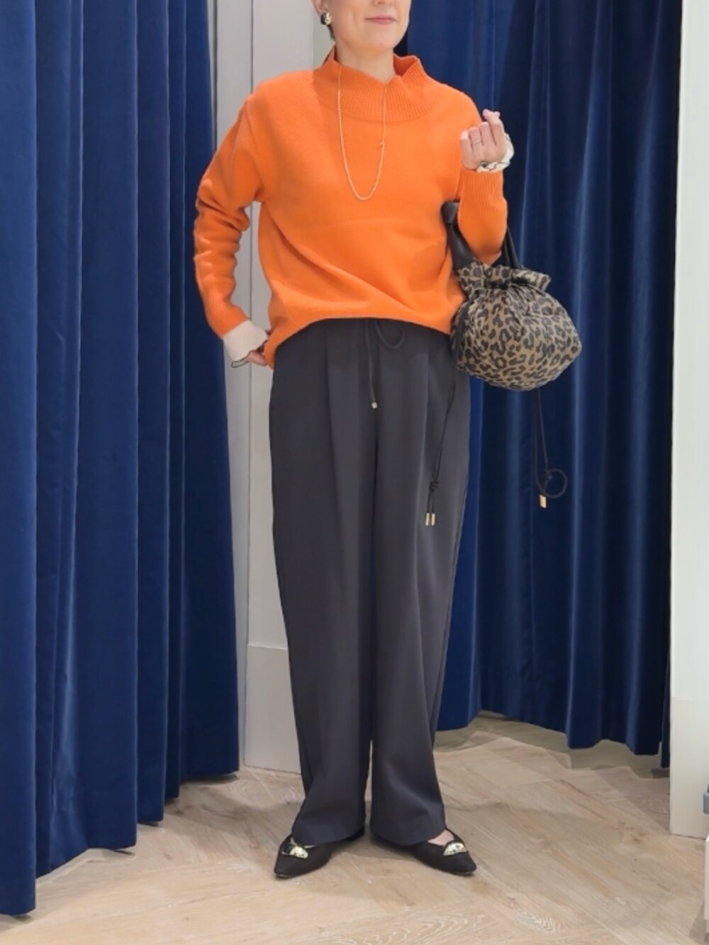 オレンジ系のニット/セーター、グレー系のその他パンツ、ホワイト系のTシャツ/カットソーを着用したレディースの冬コーディネートの8枚目の写真