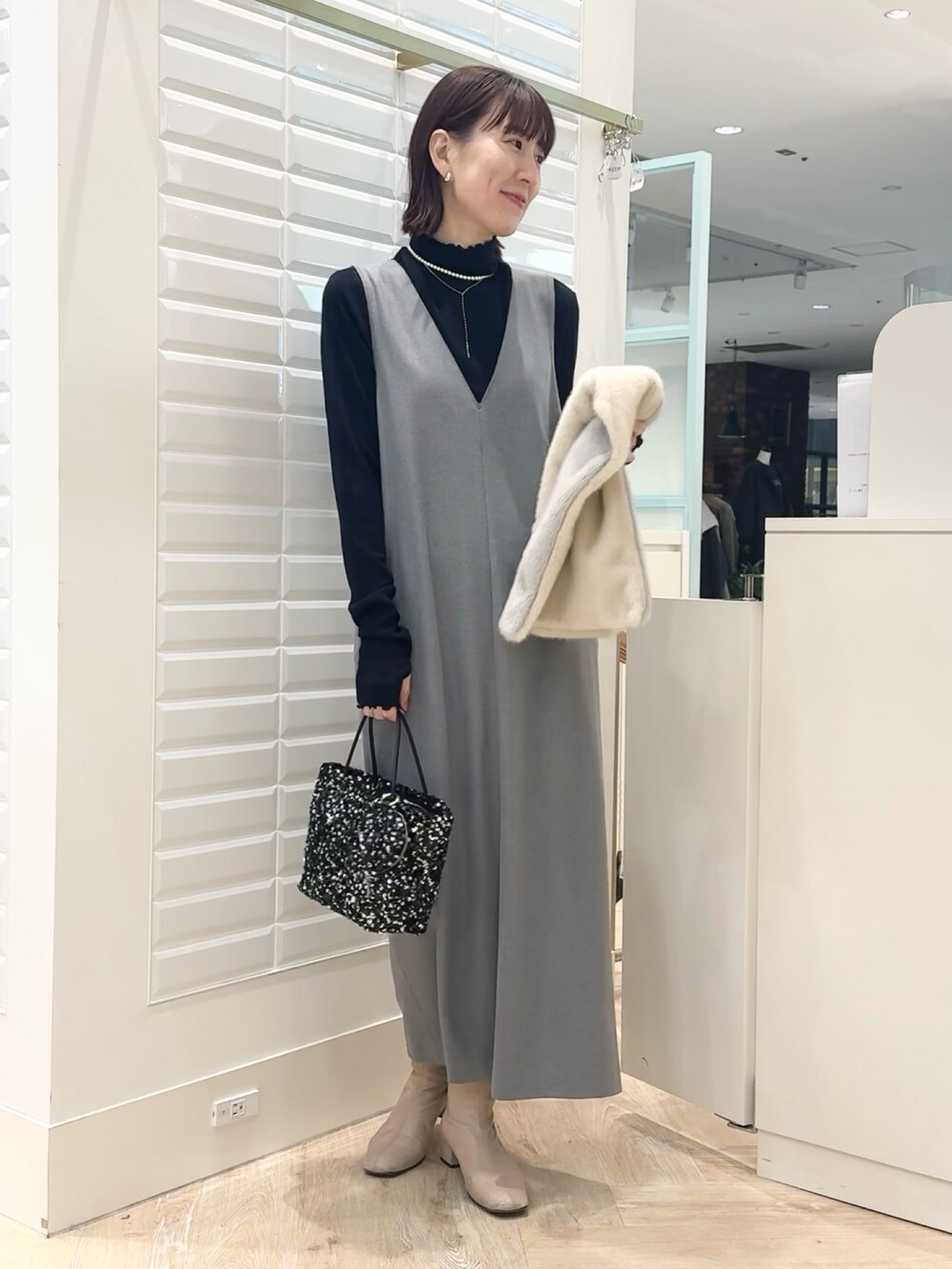 グレー系のワンピース、ブラック系のショルダーバッグ、ブルー系のTシャツ/カットソーを着用したレディースの冬コーディネートの5枚目の写真