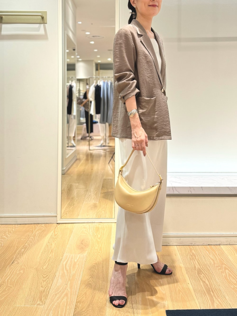 グリーン系のテーラードジャケット、ホワイト系のタンクトップ、ホワイト系のスカートを着用したレディースの夏コーディネートの9枚目の写真