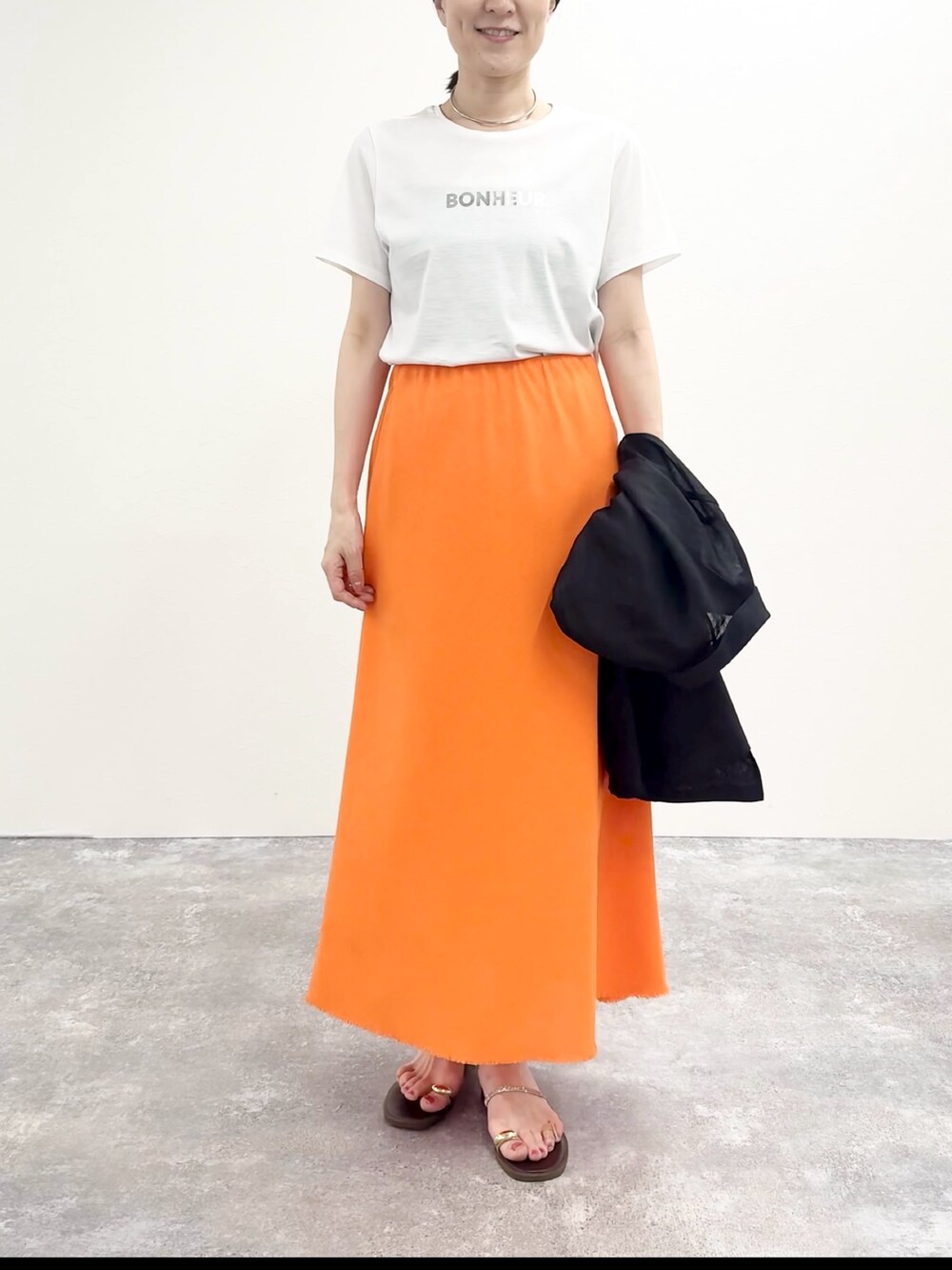 ホワイト系のTシャツ/カットソー、オレンジ系のスカート、ブラウン系のサンダルを着用したレディースの夏コーディネートの5枚目の写真