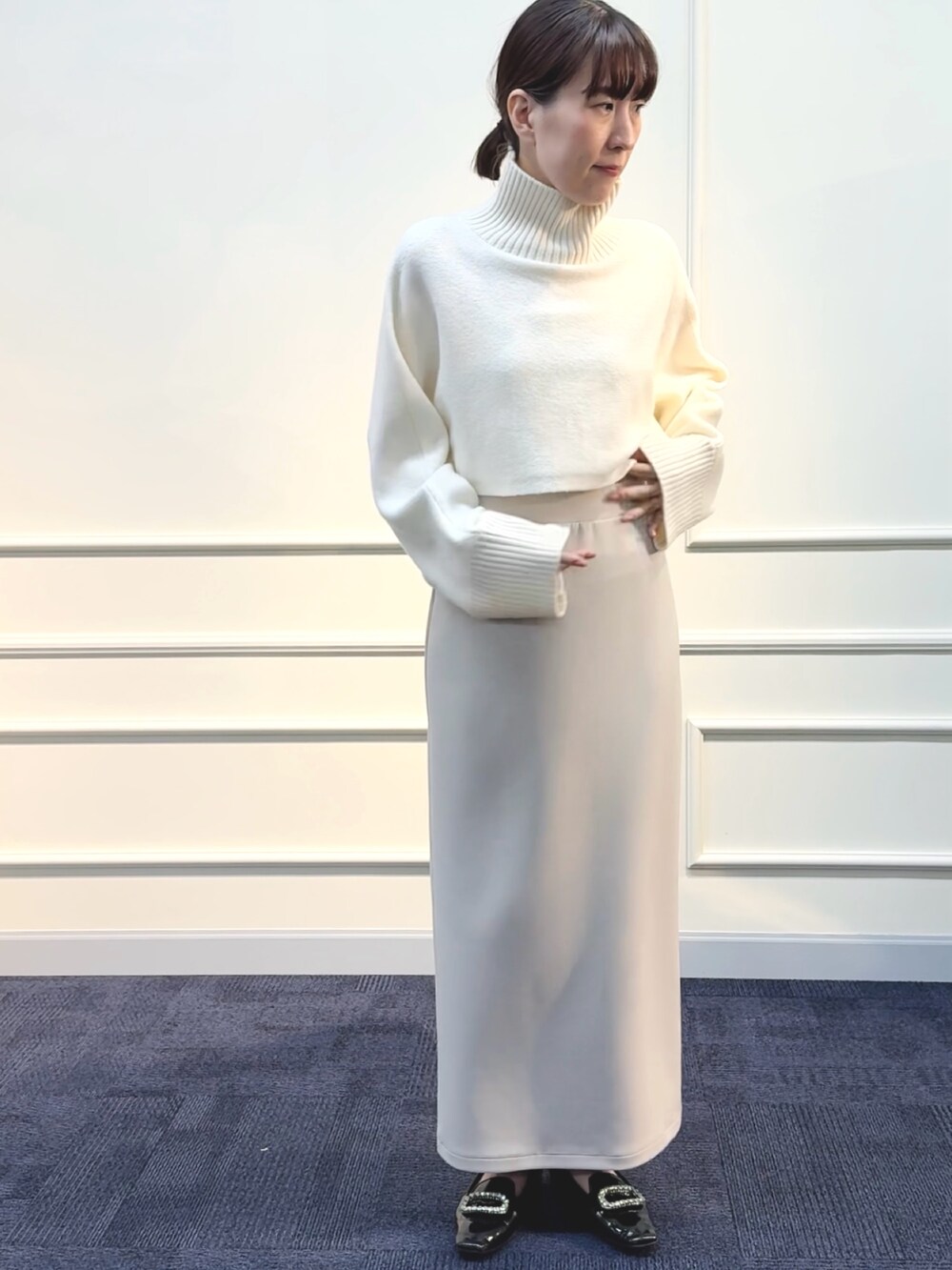 ベージュ系のスカート、ホワイト系のニット/セーターを着用したレディースの秋コーディネートの3枚目の写真