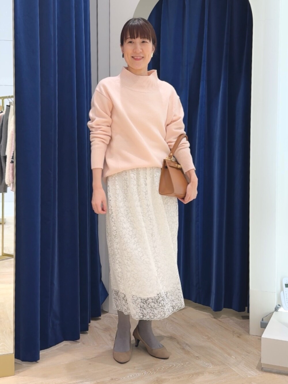 ピンク系のニット/セーター、イエロー系のショルダーバッグ、ホワイト系のスカートを着用したレディースの冬コーディネートの3枚目の写真