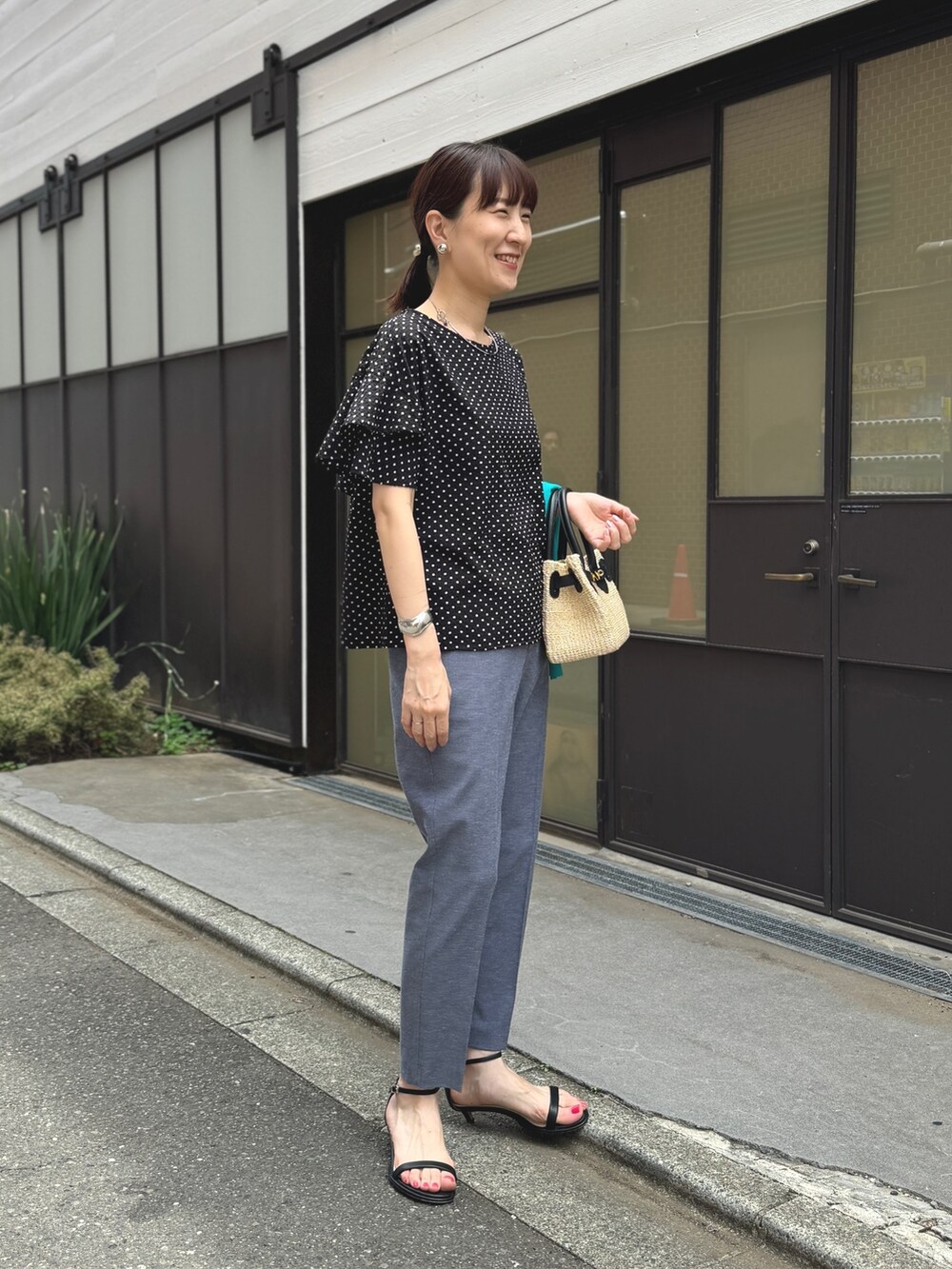 ゴールド系のサンダル、ブルー系のその他パンツ、ブラック系のかごバッグを着用したレディースの春コーディネートの3枚目の写真