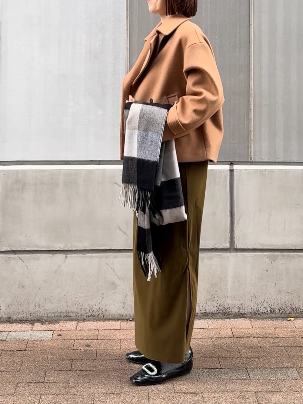 グリーン系のスカート、ホワイト系のニット/セーター、イエロー系のピーコートを着用したレディースの秋コーディネートの4枚目の写真