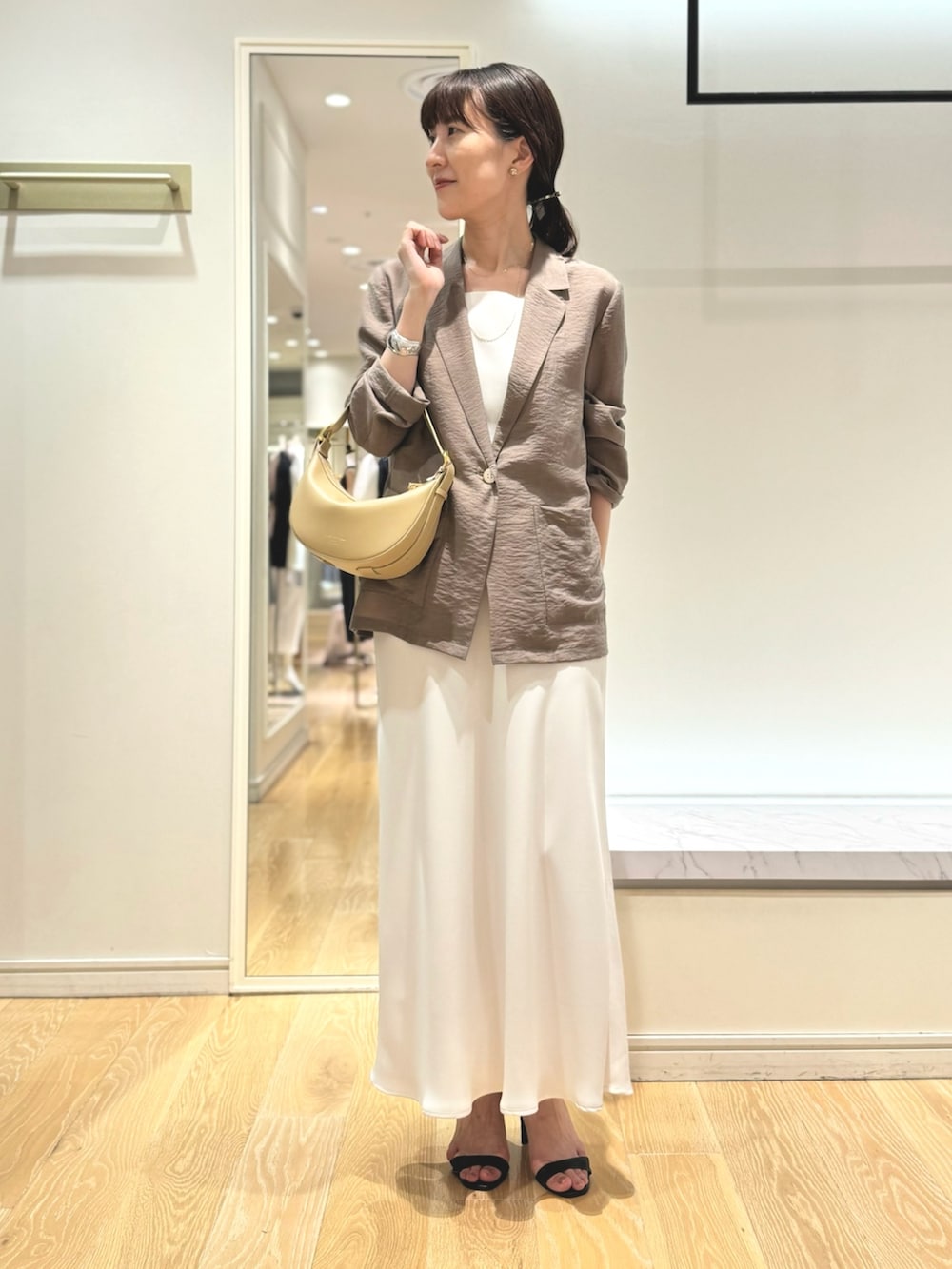 グリーン系のテーラードジャケット、ホワイト系のタンクトップ、ホワイト系のスカートを着用したレディースの夏コーディネートの8枚目の写真