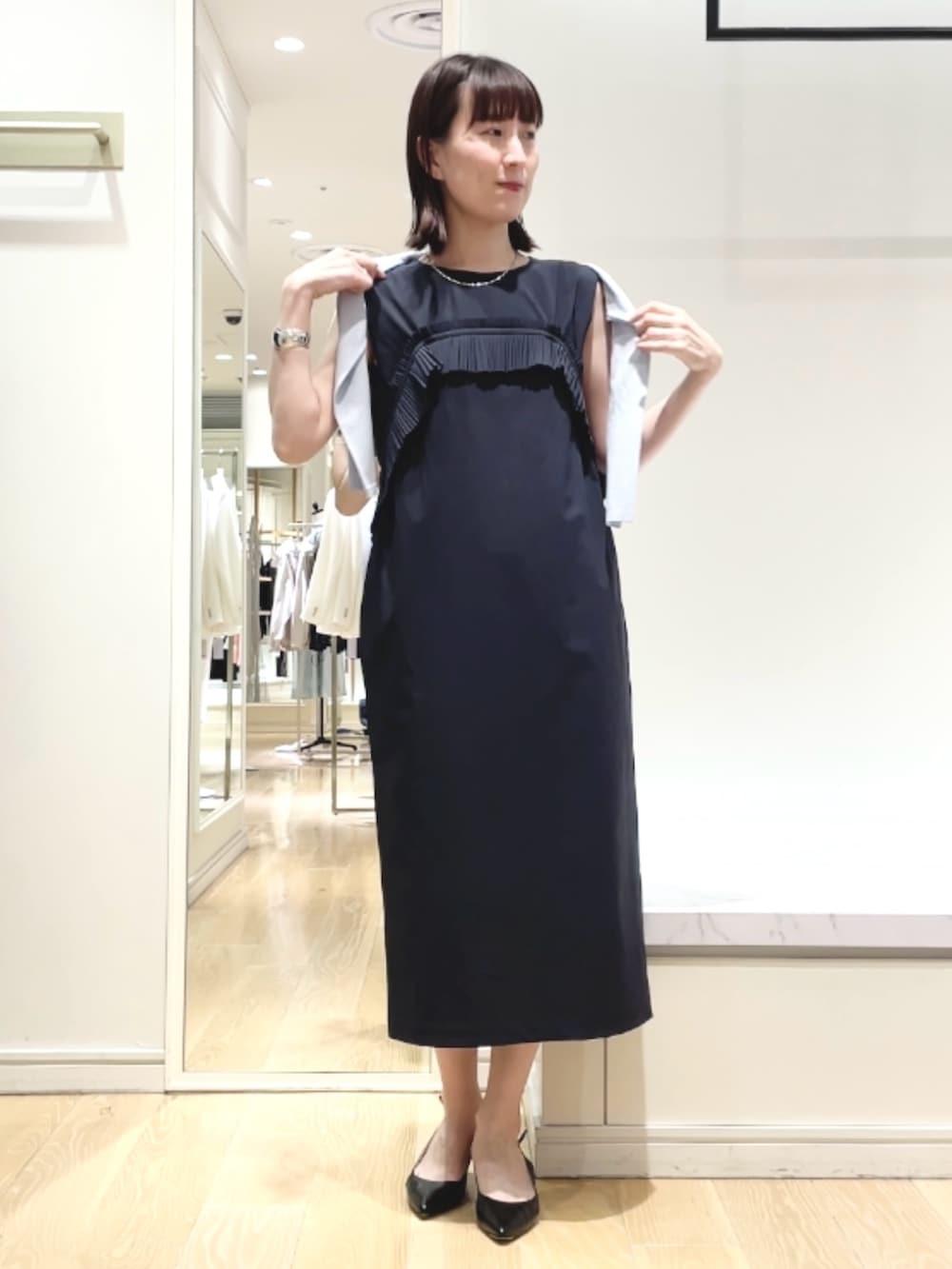 ブラック系のパンプス、ブルー系のワンピース、シルバー系のネックレスを着用したレディースの春コーディネートの2枚目の写真