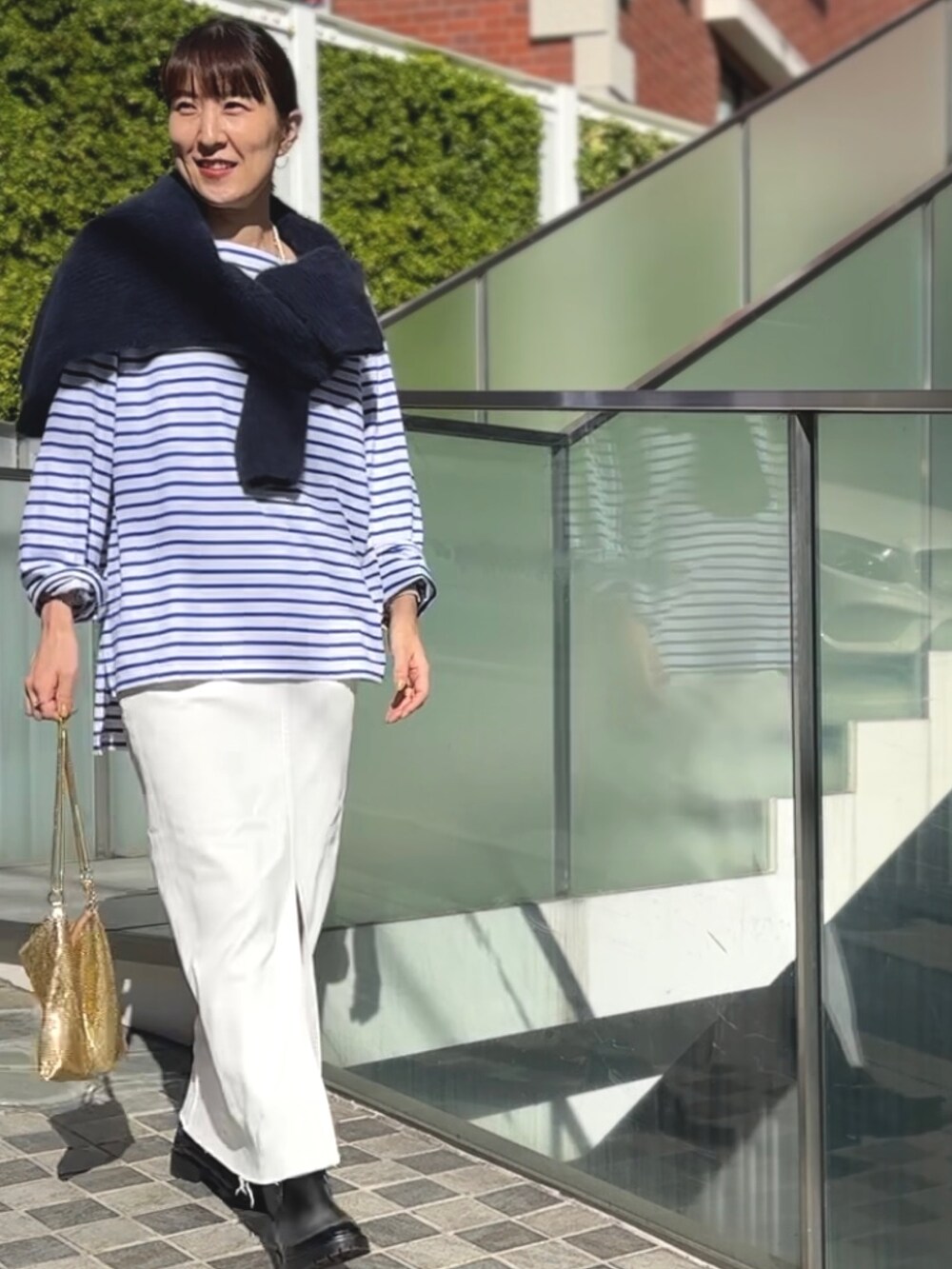 ゴールド系のクラッチバッグ、ブラック系のブーツ、ホワイト系のデニムスカートを着用したレディースの冬コーディネートの8枚目の写真