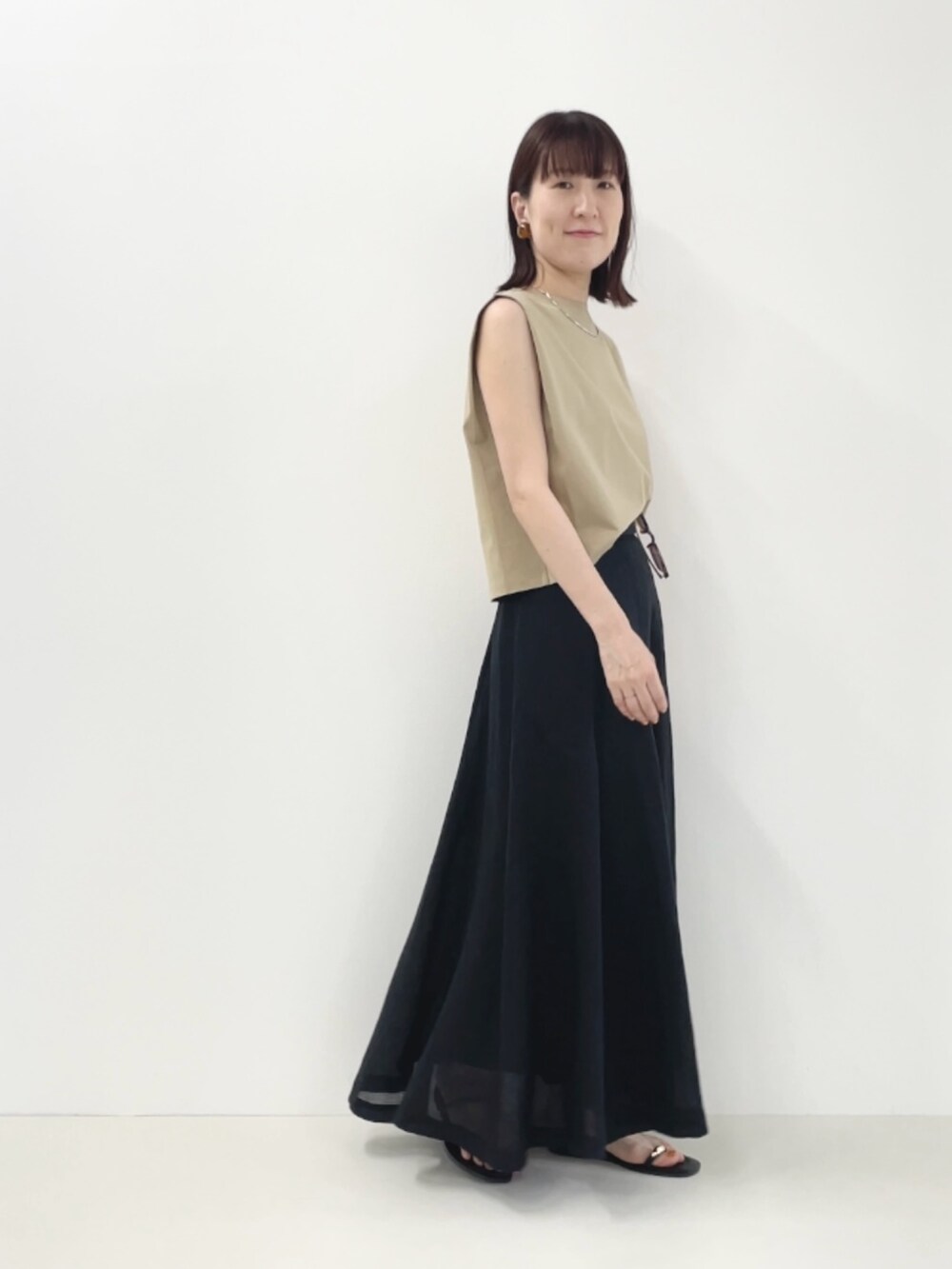 ブラック系のサンダル、ベージュ系のTシャツ/カットソー、ブラック系のスカートを着用したレディースの夏コーディネートの9枚目の写真