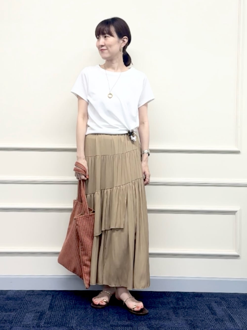 レッド系のトートバッグ、イエロー系のスカート、ホワイト系のTシャツ/カットソーを着用したレディースの夏コーディネートの5枚目の写真