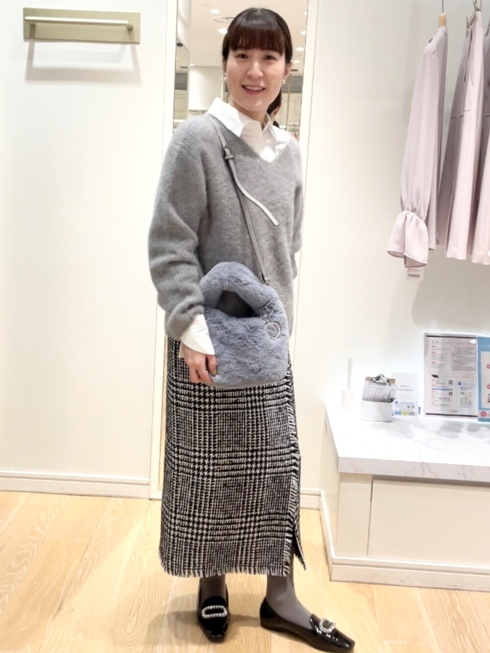 ブラック系のスカート、グレー系のニット/セーター、ブルー系のトートバッグを着用したレディースの冬コーディネートの4枚目の写真