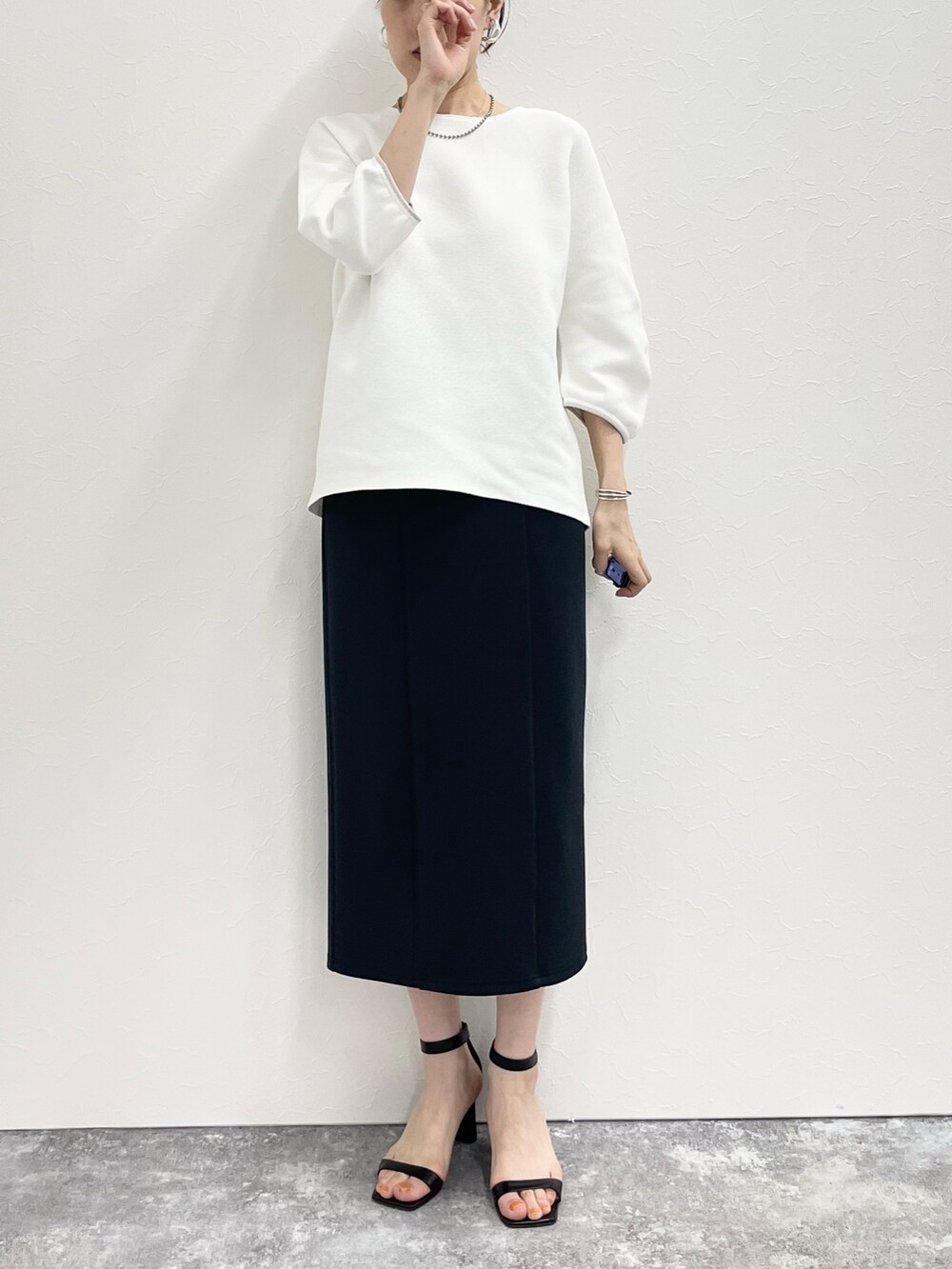 ブラック系のスカート、ホワイト系のニット/セーターを着用したレディースの春コーディネートの2枚目の写真