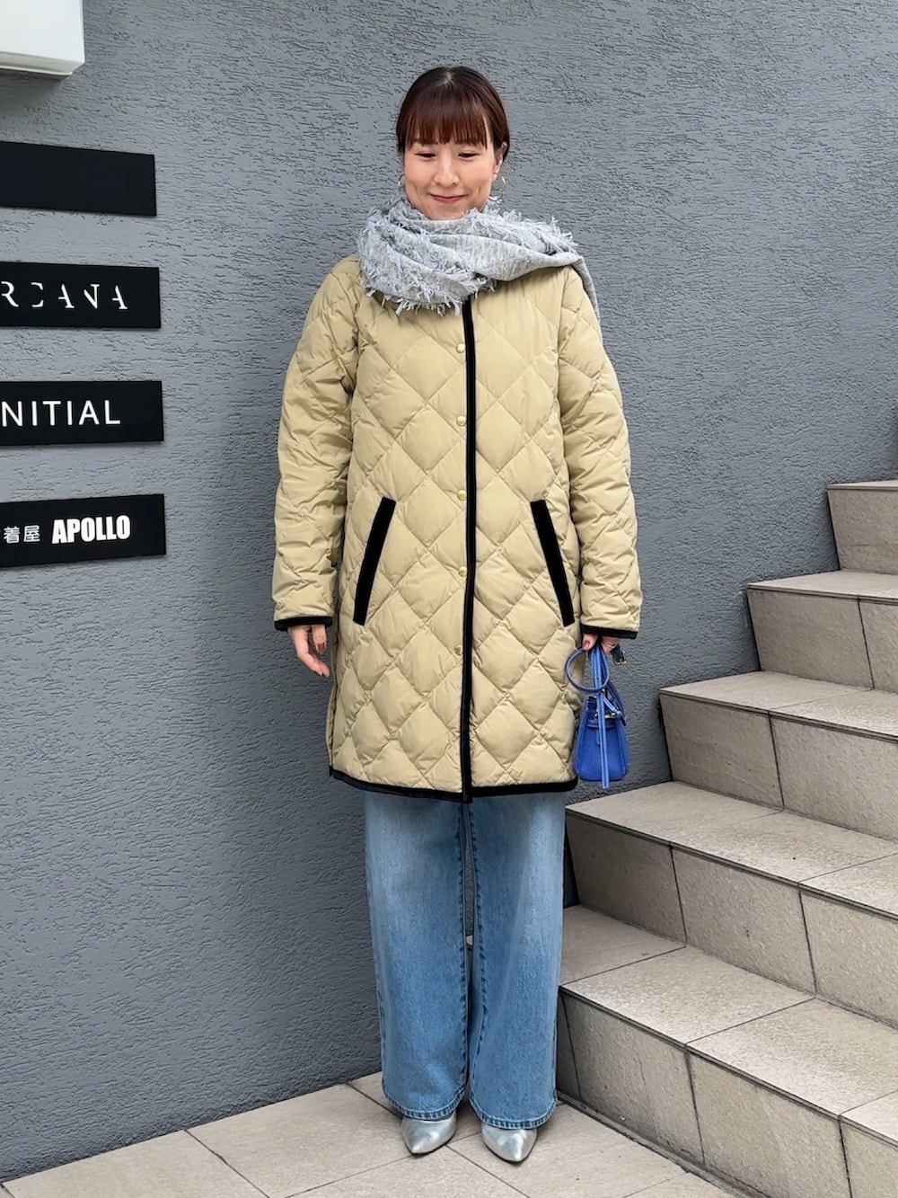 ブルー系のデニムパンツ、ブルー系のショルダーバッグ、ベージュ系のダウンジャケット/コートを着用したレディースの秋コーディネートの6枚目の写真