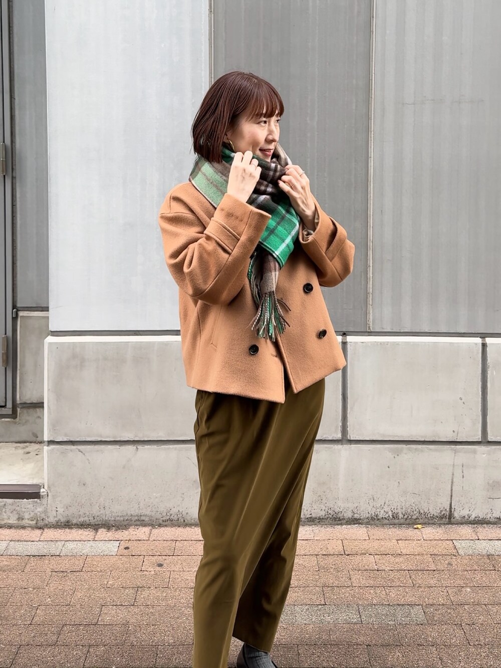 グリーン系のスカート、ホワイト系のニット/セーター、イエロー系のピーコートを着用したレディースの秋コーディネートの3枚目の写真