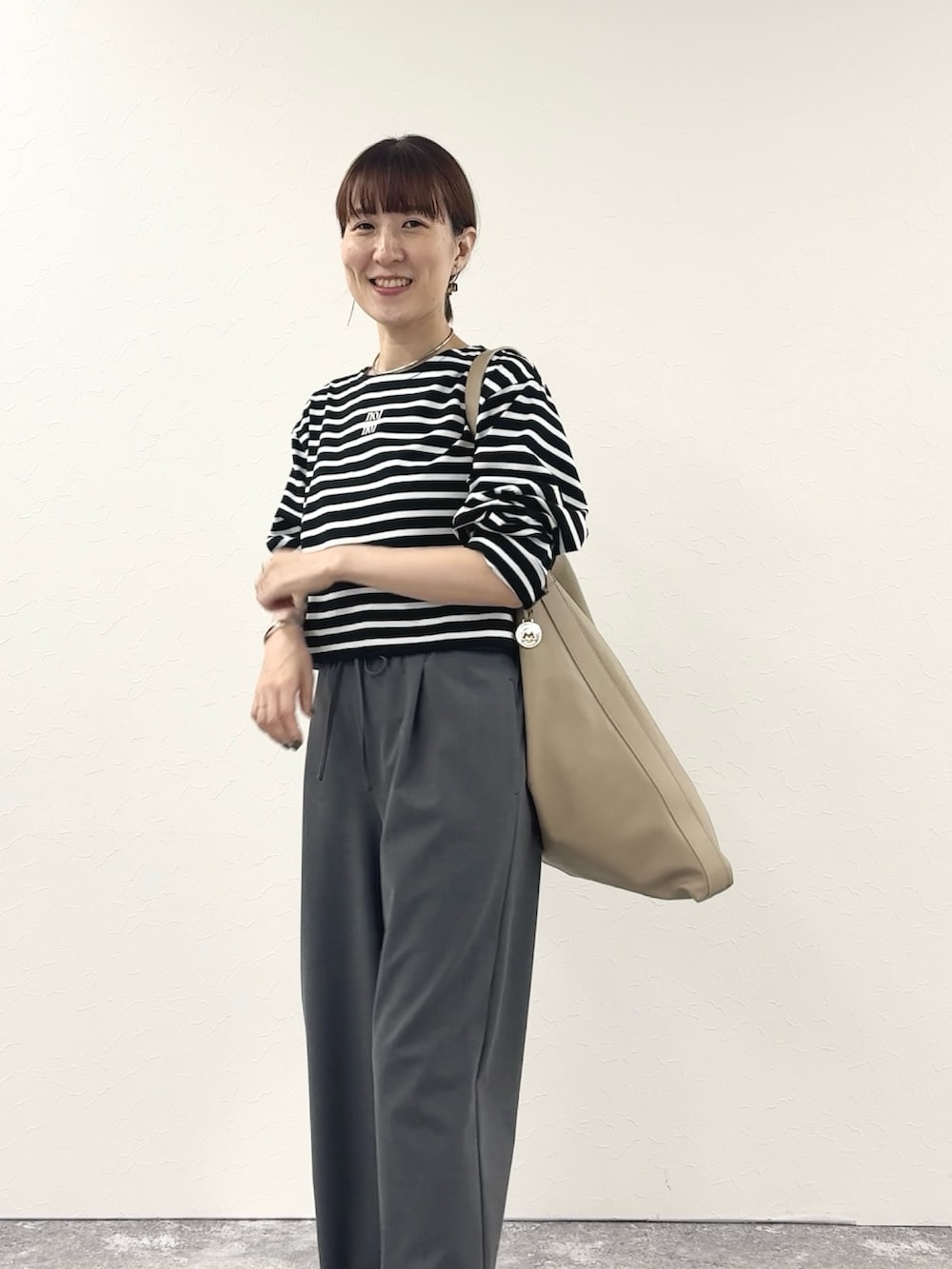 ブラック系のTシャツ/カットソー、ベージュ系のショルダーバッグ、グレー系のその他パンツを着用したレディースの秋コーディネートの10枚目の写真