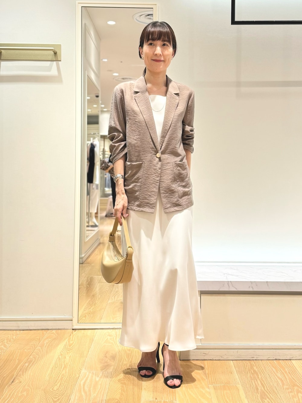 グリーン系のテーラードジャケット、ホワイト系のタンクトップ、ホワイト系のスカートを着用したレディースの夏コーディネートの4枚目の写真