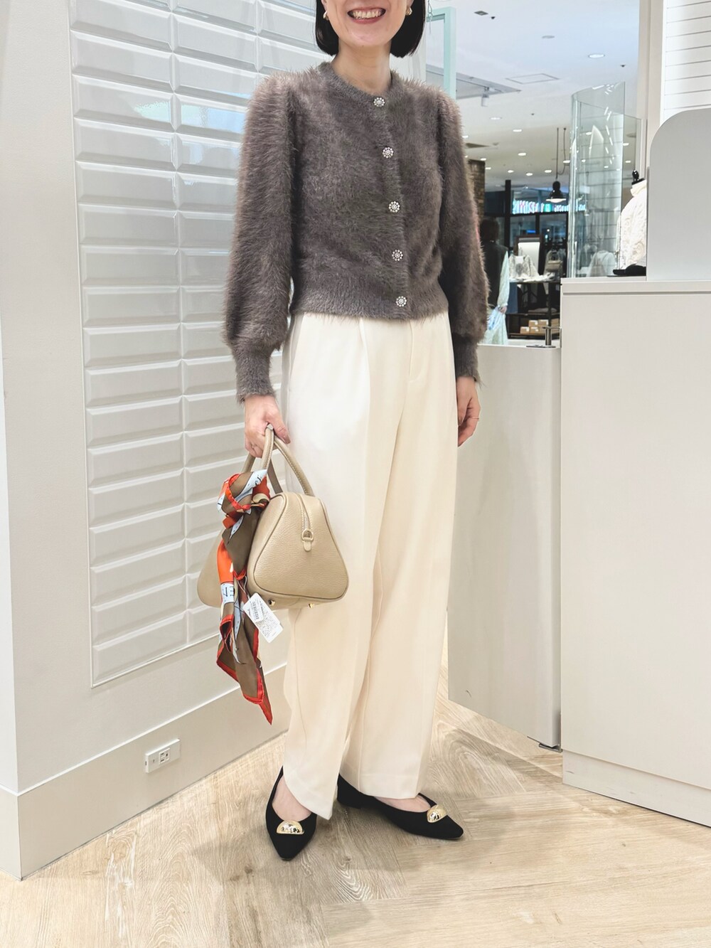 ベージュ系のショルダーバッグ、ブラウン系のカーディガン/ボレロ、ホワイト系のその他パンツを着用したレディースの秋コーディネートの5枚目の写真