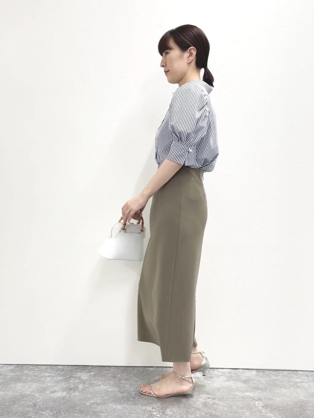シルバー系のサンダル、グリーン系のスカート、ホワイト系のショルダーバッグを着用したレディースの春コーディネートの4枚目の写真