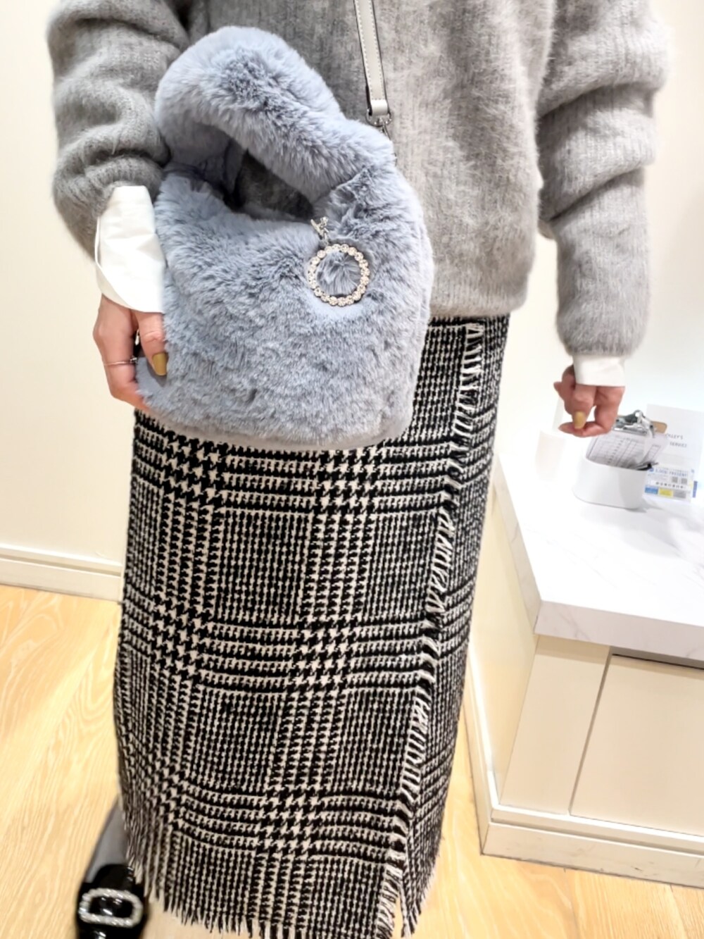 ブラック系のスカート、グレー系のニット/セーター、ブルー系のトートバッグを着用したレディースの冬コーディネートの5枚目の写真