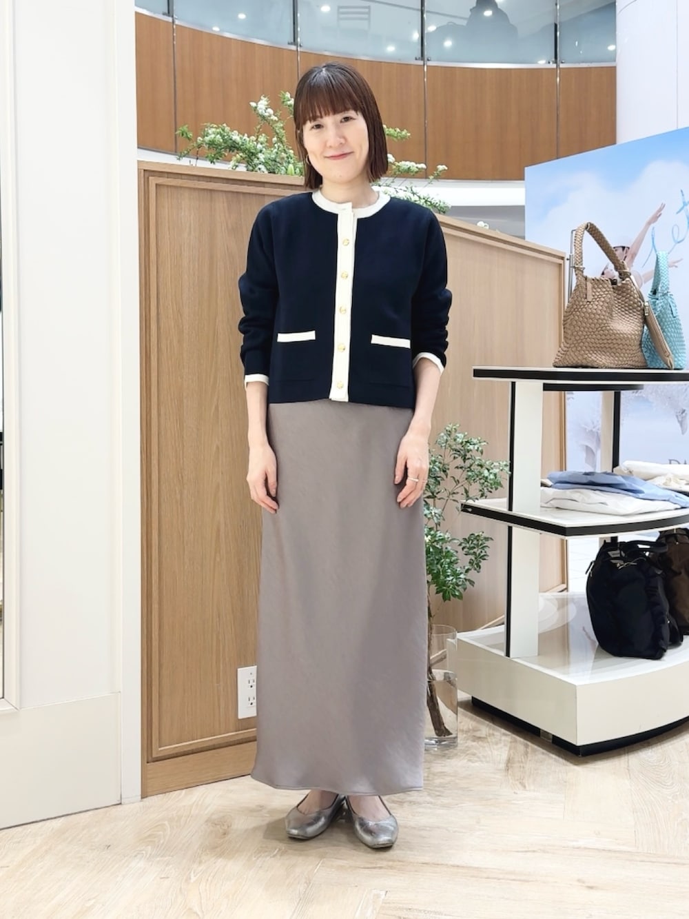 グリーン系のスカート、ベージュ系のトートバッグ、ブルー系のカーディガン/ボレロを着用したレディースの春コーディネートの2枚目の写真