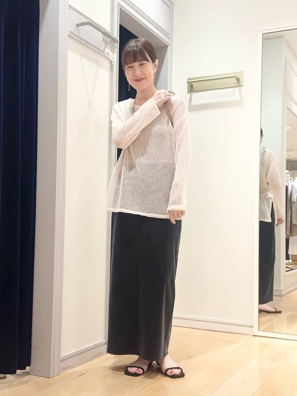 ブラック系のスカート、ベージュ系のショルダーバッグ、ホワイト系のニット/セーターを着用したレディースの夏コーディネートの4枚目の写真