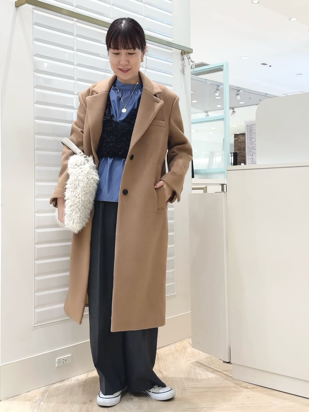 グレー系のベスト、ブルー系のシャツ/ブラウス、ホワイト系のショルダーバッグを着用したレディースの秋コーディネートの2枚目の写真