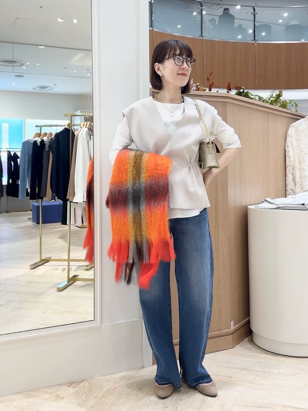 ブルー系のデニムパンツ、ベージュ系のベスト、ホワイト系のシャツ/ブラウスを着用したレディースの秋コーディネートの4枚目の写真