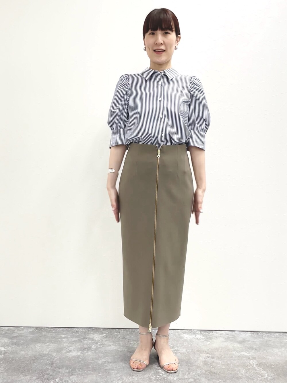 シルバー系のサンダル、グリーン系のスカート、ホワイト系のショルダーバッグを着用したレディースの春コーディネートの8枚目の写真