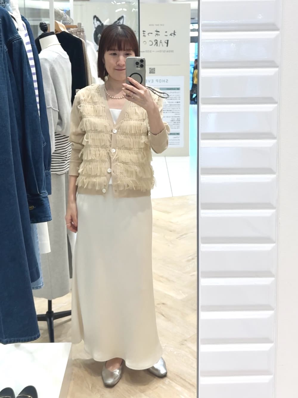 ホワイト系のスカート、ホワイト系のタンクトップ、ベージュ系のカーディガン/ボレロを着用したレディースの春コーディネートの4枚目の写真