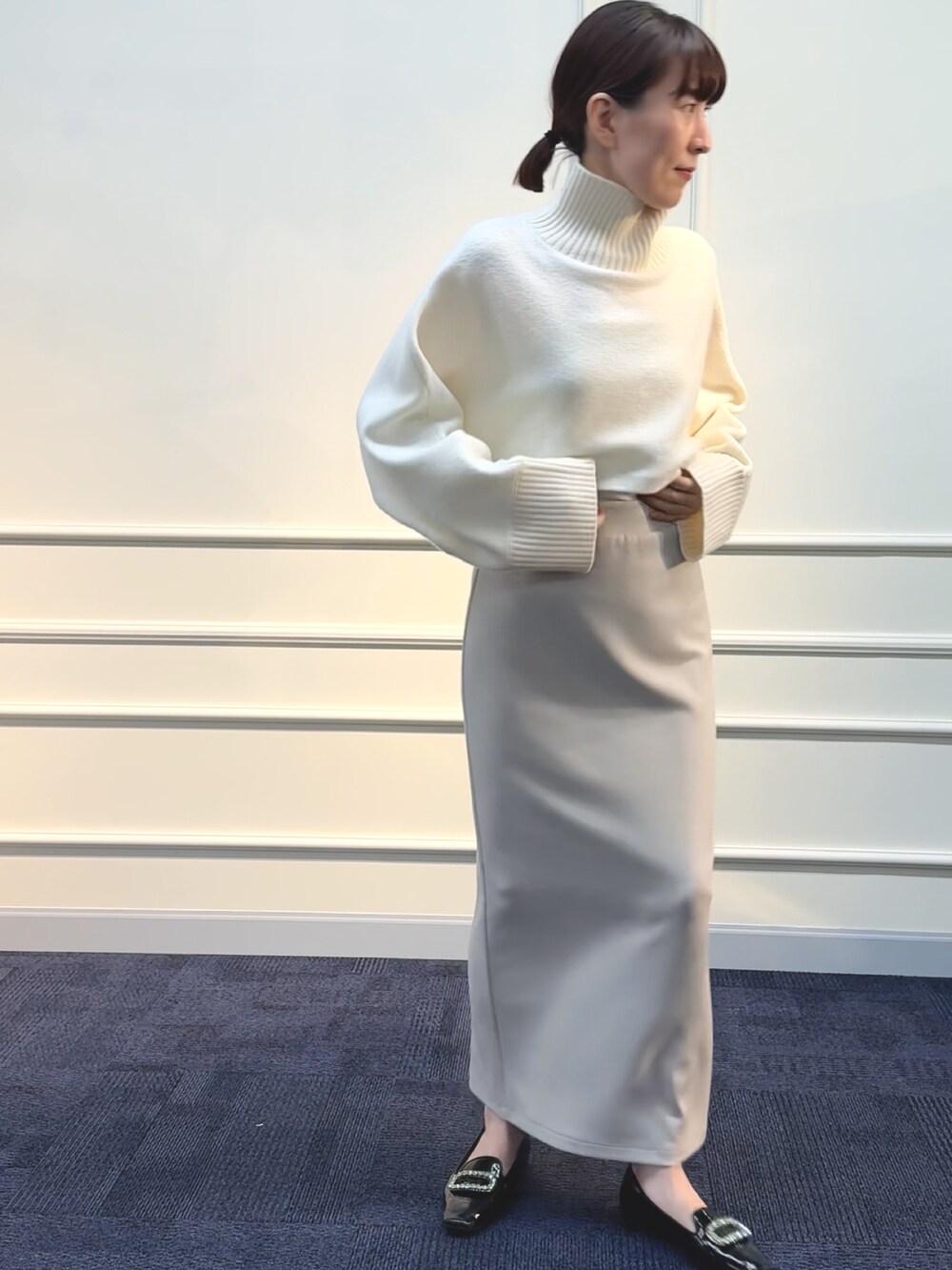 ベージュ系のスカート、ホワイト系のニット/セーターを着用したレディースの秋コーディネートの6枚目の写真