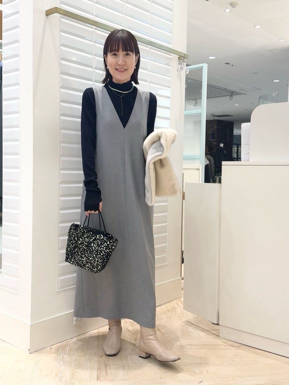 グレー系のワンピース、ブラック系のショルダーバッグ、ブルー系のTシャツ/カットソーを着用したレディースの冬コーディネートの4枚目の写真
