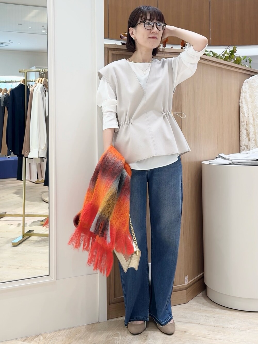 ブルー系のデニムパンツ、ベージュ系のベスト、ホワイト系のシャツ/ブラウスを着用したレディースの秋コーディネートの2枚目の写真