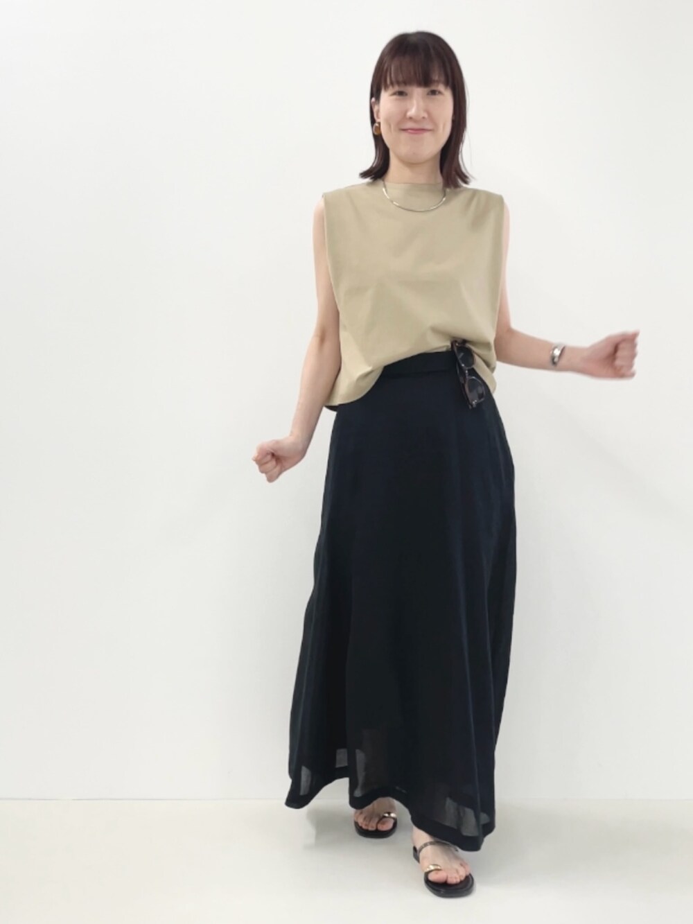 ブラック系のサンダル、ベージュ系のTシャツ/カットソー、ブラック系のスカートを着用したレディースの夏コーディネートの6枚目の写真