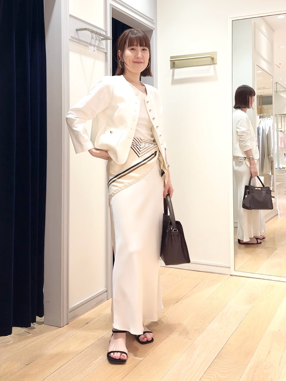 ホワイト系のタンクトップ、ホワイト系のノーカラージャケット、ホワイト系のスカートを着用したレディースの春コーディネートの3枚目の写真