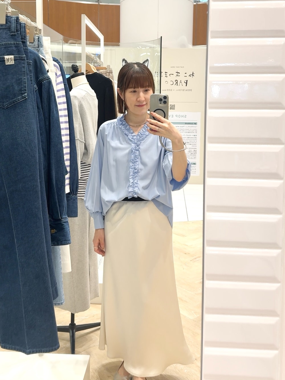 ブルー系のシャツ/ブラウス、ホワイト系のスカート、グレー系のネックレスを着用したレディースの春コーディネートの5枚目の写真