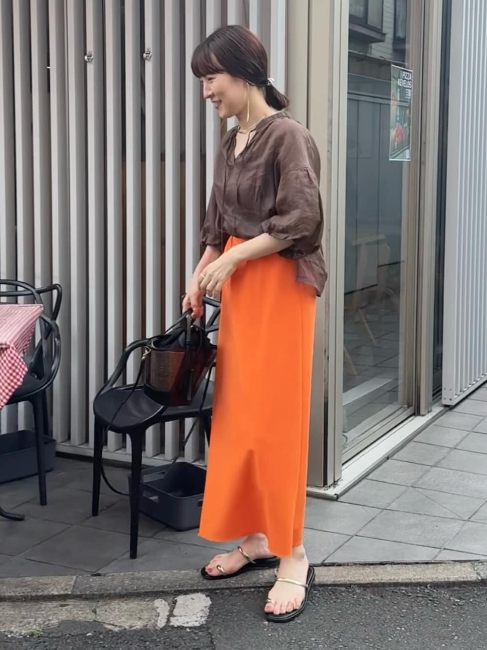 ブラック系のかごバッグ、オレンジ系のスカート、ブラウン系のシャツ/ブラウスを着用したレディースの夏コーディネートの3枚目の写真