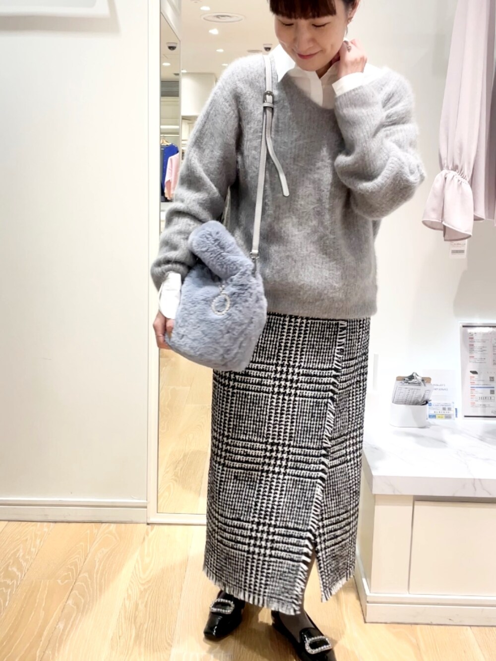 ブラック系のスカート、グレー系のニット/セーター、ブルー系のトートバッグを着用したレディースの冬コーディネートの6枚目の写真