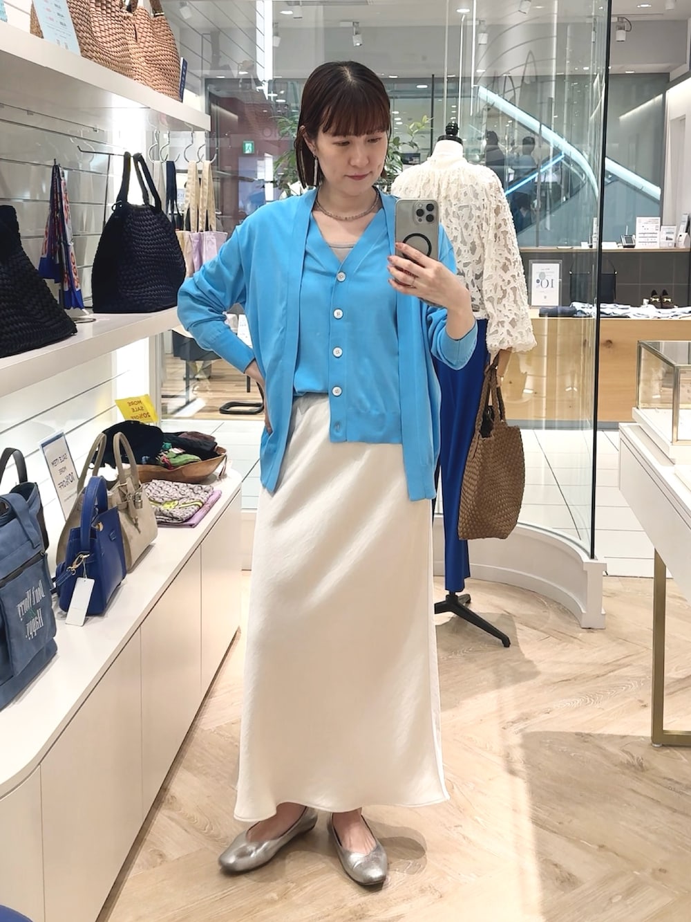 ホワイト系のスカート、ブルー系のカーディガン/ボレロ、グレー系のネックレスを着用したレディースの春コーディネートの3枚目の写真